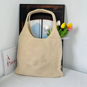 Close-up of beige crochet knit tote bag with hollow pattern texture and tulip decor