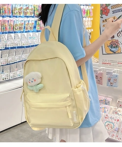 Detail of yellow nylon backpack with cloud plush charm and side fashion label