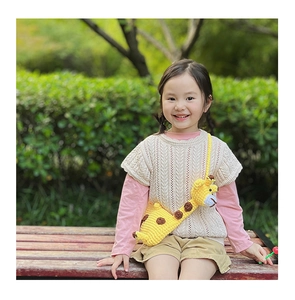 Detail of a handmade yellow crochet giraffe crossbody bag for a young girl outdoors
