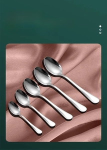 Macro view of five different sizes of polished stainless steel spoons on purple silk