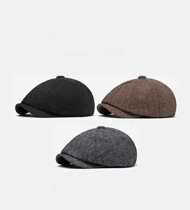 Detailed view of three herringbone newsboy caps in black, dark brown and mottled grey
