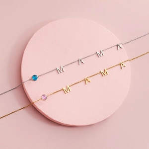 Detail of gold and silver MAMA necklaces with round pink and blue gemstones