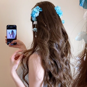 Détail de fleurs en soie bleue avec d'élégants pendentifs en perles sur une barrette