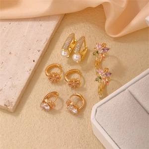Collection de boucles d'oreilles fleurs dorées avec perles et zircons sur tissu en soie