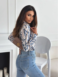 Detail of long sleeve blouse with blue leopard print and high waist denim jeans