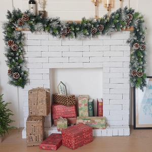 Detail of lush green Christmas garland with natural pine cones and festive gift boxes