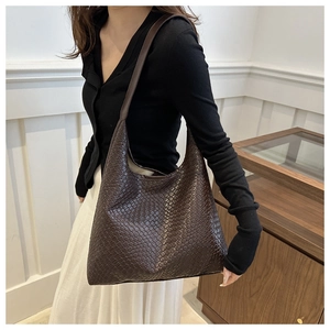 Close-up of the large woven texture tote bag showing the deep coffee leather craftsmanship