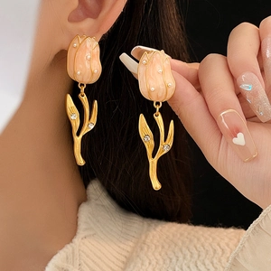 Close-up of pink tulip earrings with pearls and rhinestones on elegant gold metal stems