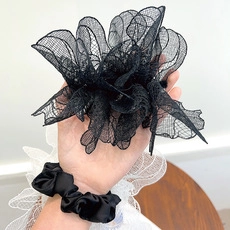 Close-up of black lace scrunchie and silk hair tie worn on wrist with professional focus