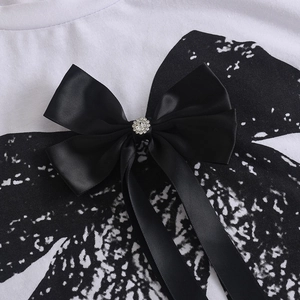 Détail d'un nœud en satin noir avec strass brillants sur un tissu blanc doux
