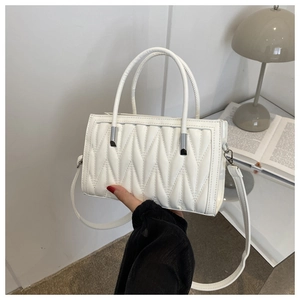 Detail of white pleated handbag with quilted texture and silver hardware accents