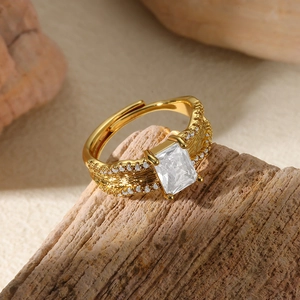 Detail of gold open ring featuring large rectangular zircon and feather texture on wood