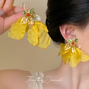 Macro detail of oversized yellow floral earrings with silk petals and beaded center