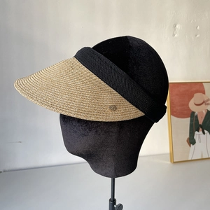 Close-up of woven straw sun visor with black elastic band and gold metal detail