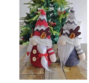 Détail de gnomes de Noël en peluche avec bois de renne posés sur une surface en bois
