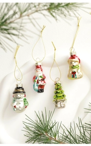 Close-up of glass Christmas ornaments with snowman and Santa shapes on pine branches