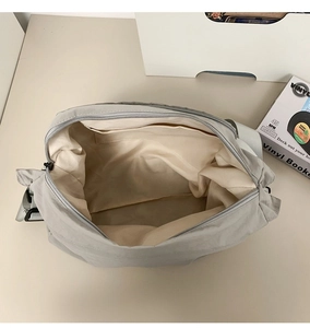 Internal view showing a beige lining and functional open pocket of a nylon messenger bag