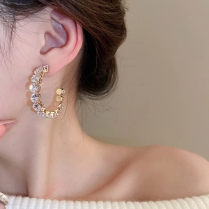 Close-up of elegant gold C-shaped hoop earrings with sparkling rhinestones on model