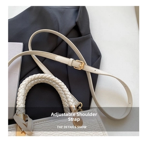 Detail of beige bucket bag featuring crocodile texture and an adjustable shoulder strap