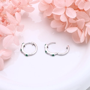 Close-up of S925 sterling silver hoop earrings with emerald green and clear gemstones