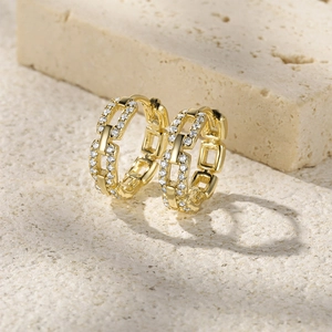 Detailed macro view of gold-plated chain-link earrings set with sparkling zircon stones