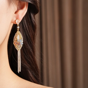 Dettaglio dell'orecchino a foglia d'oro con strass, perline e nappe in argento