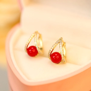 Macro detail of elegant gold-plated pearl earrings inside a pink heart-shaped gift box