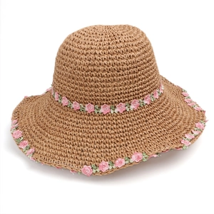 Detailed macro view of woven straw sun hat featuring pink lace flower embroidery textures