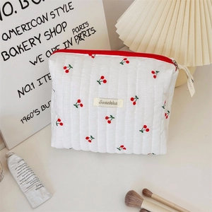 Close-up of quilted cherry print makeup bag with a red zipper and Suzakka brand label