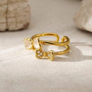 Detailed close-up of double-layer gold ring with opal bow and rhinestone accents