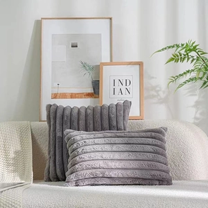 Detail of grey faux rabbit fur pillow covers with stripe texture on white fabric sofa