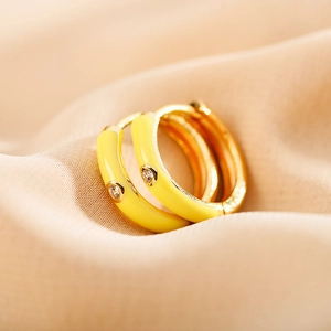 Macro shot of yellow enamel hoop earrings with a single centered diamond accent