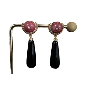 Vintage style drop earrings with pink stones and black teardrop pendants on a gold stand