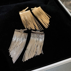 Detail view of gold and silver curved bar long chain tassel earrings in a black velvet box