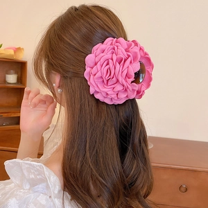 Detail of a large pink fabric rose hair claw clip worn on a low bun in an elegant setting