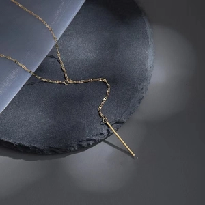 Gold stainless steel Y-shaped tassel necklace with long bar pendant on rock background