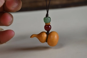 Detail of a carved red sandalwood gourd pendant with colorful beads and brown rope