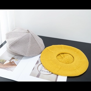 Close-up of beige and ginger yellow knitted beret hats with detailed wool texture