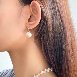 Close-up of elegant 925 sterling silver pearl earrings worn by a model in soft lighting