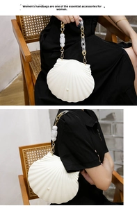 Detailed view of white shell-shaped acrylic clutch with pearl accent and acrylic chain