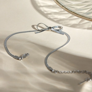Detail of silver snake chain necklace with a bow pendant and lobster clasp closure