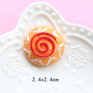 Macro shot of 2.4cm resin orange miniature dessert with red spiral on a relief plate