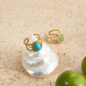 Detail of 18K gold stainless steel rings with turquoise stones on a seashell