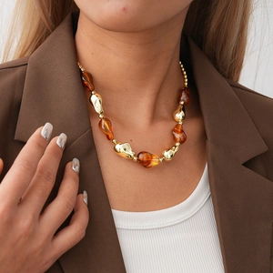 Close-up of golden metal and amber irregular resin beads necklace on a model clothing