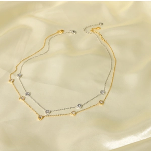 Detail of 18k gold and silver heart necklaces with zircons on beige silk
