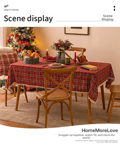 Close-up of red plaid Christmas tablecloth with white pom-pom fringe and holiday texture