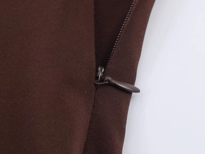 Dettaglio della trama del tessuto marrone scuro e chiusura con zip in metallo coordinata
