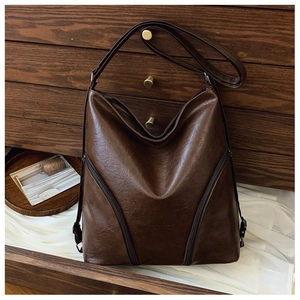Detailed view of brown PU leather shoulder bag featuring dual diagonal zipper pockets