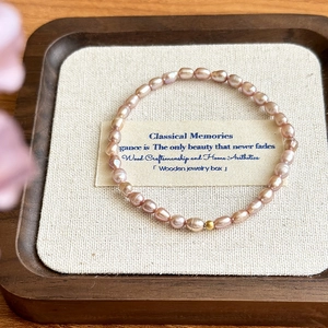 Detail of pink freshwater pearl bracelet with 14K gold bead on a linen jewelry display