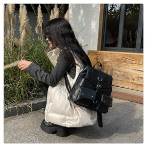 Side view of a vintage black faux leather backpack worn by a model in a natural outdoor setting